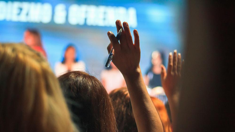 Woman raises hand at an event
